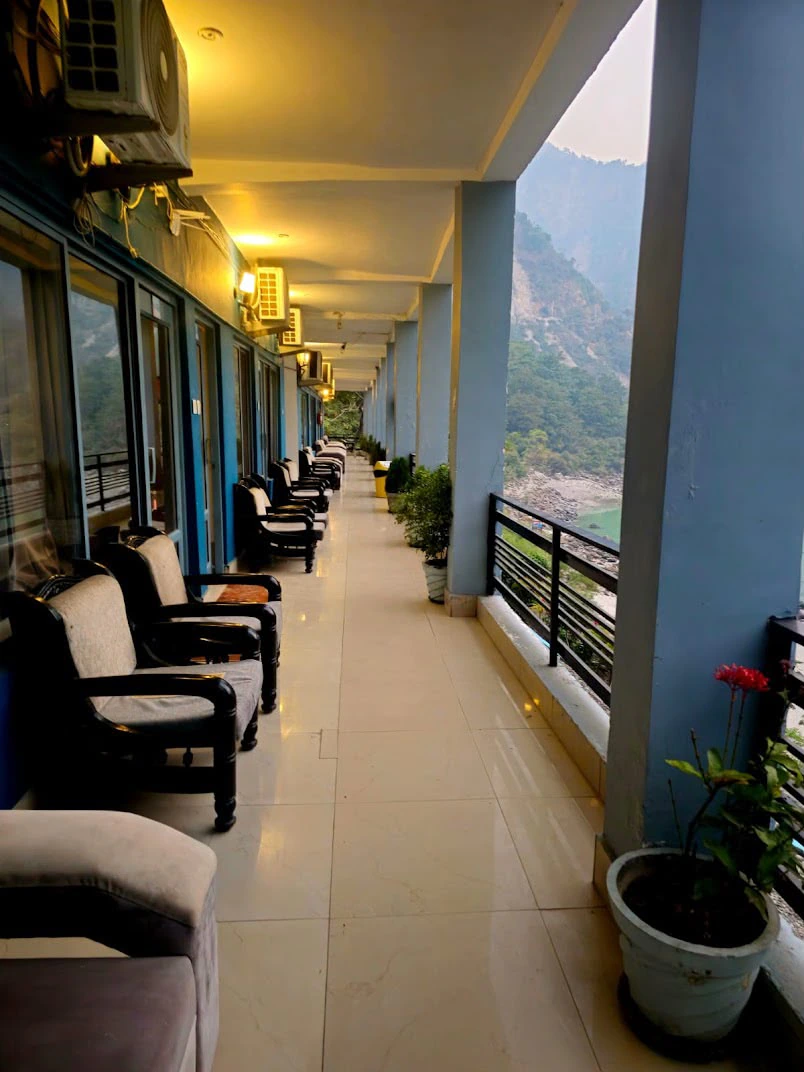 Retreat open-air balcony corridor with armchairs overlooking the Ganga river and mountains